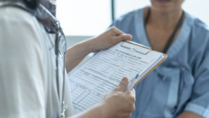 Doctor reviewing a chart while talking to a patient.